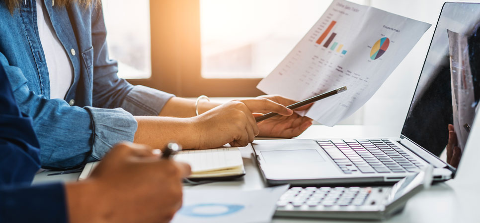 Produtores rurais analisando gráficos e dados financeiros no fechamento de safra com uso de planilhas e notebook